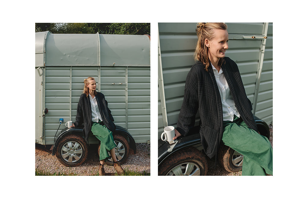 olivia-sat-on-the-wheel-of-her-trailer-wearing-a-white-shirt-black-quilted-jacket-and-green-cord-trousers