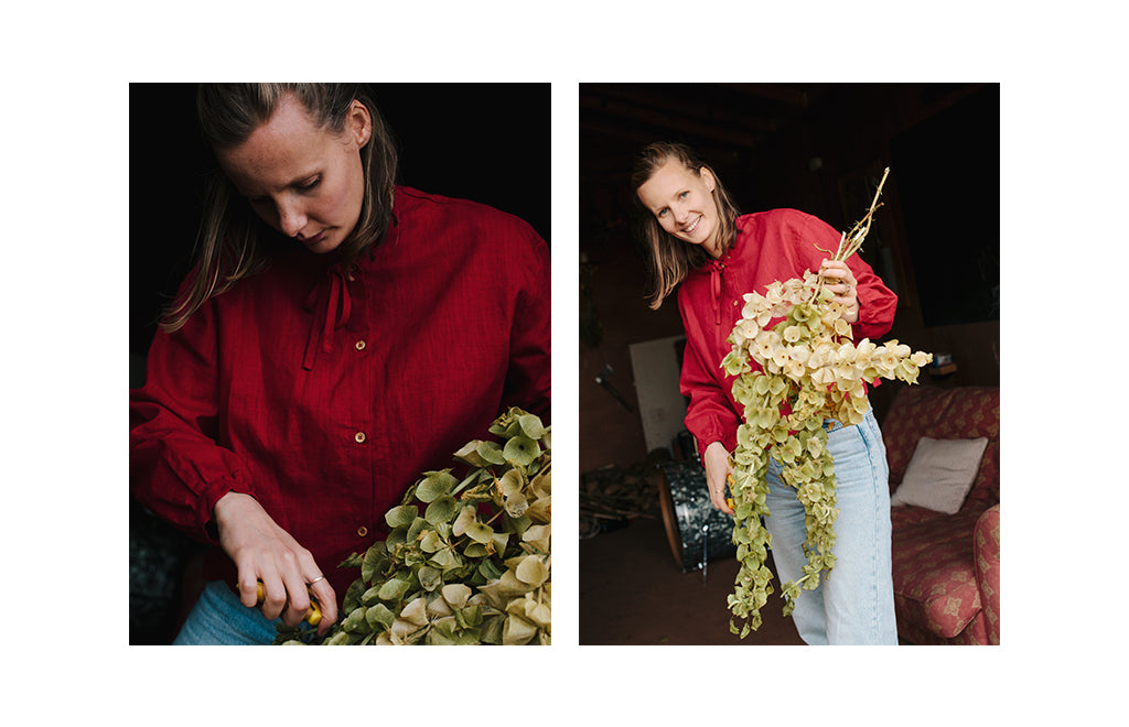 olivia-wears-the-tie-shirt-in-red-linen-with-light-blue-jeans-holding-foliage